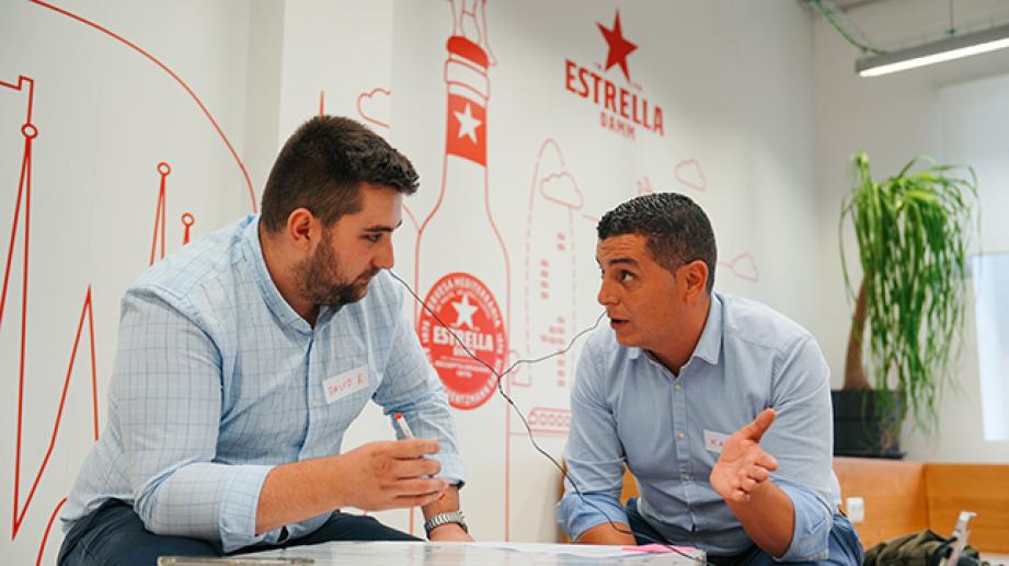 dues persones parlant en una reunió