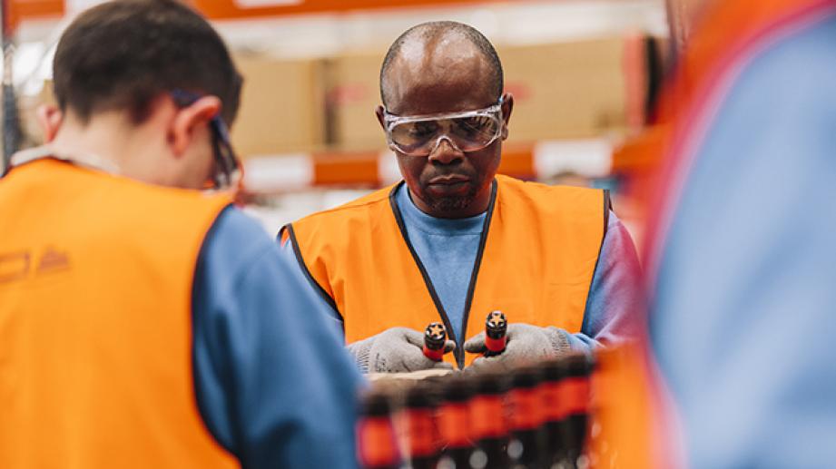 man picking up two bottles in brewery