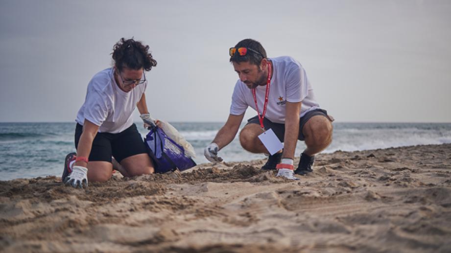 dues persones recollint residus en platja
